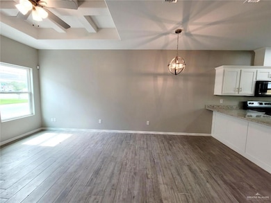 Kitchen featuring white cabinets, ceiling fan with notable chandelier, light stone countertops, dark wood-type flooring, and electric stove