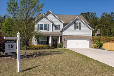 Craftsman house featuring a front lawn, concrete driveway, covered porch, and brick siding