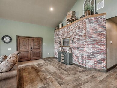 Living room with wood finished floors, high vaulted ceiling, and brick wall
