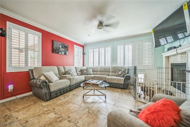 Tiled living area with crown molding, ceiling fan,