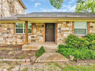 Doorway to property featuring stone siding and a s
