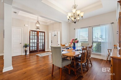 Dining room featuring dark wood-type flooring, french doors, a chandelier, and a tray ceiling