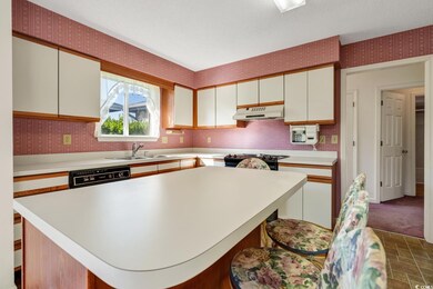Kitchen featuring wallpapered walls, under cabinet range hood, light countertops, dishwasher, and white cabinetry