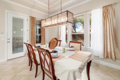 Dining space with light tile patterned floors, a chandelier, ornamental molding, and a tray ceiling