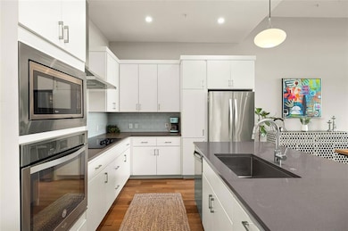 Kitchen featuring appliances with stainless steel finishes, dark countertops, backsplash, dark wood-style floors, and pendant lighting