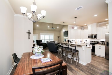 Dining area featuring a chandelier, dark wood-style flooring, a ceiling fan, recessed lighting, and ornamental molding