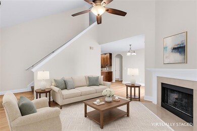 Living area with stairway, ceiling fan, arched walkways, a fireplace, and light wood finished floors