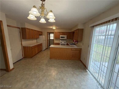 Kitchen featuring light countertops, healthy amount of natural light, white appliances, a peninsula, and a textured ceiling. NOTE:  Left side of picture is door to garage, Right side are sliders to patio. thFar end is the laundry room