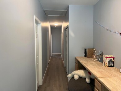 Hallway with attic access and dark wood-type flooring