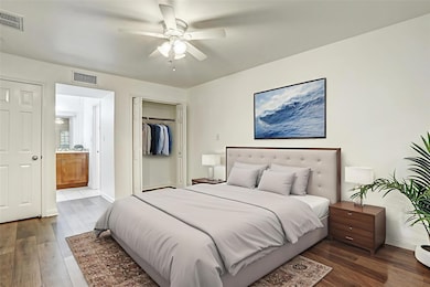 Bedroom with wood finished floors, a closet, ensu