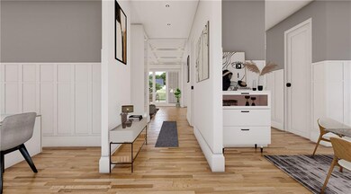 Hall featuring light wood-style flooring, a decorative wall, and a wainscoted wall