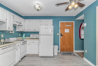 Kitchen with white appliances, under cabinet range hood, ceiling fan, light countertops, and white cabinetry