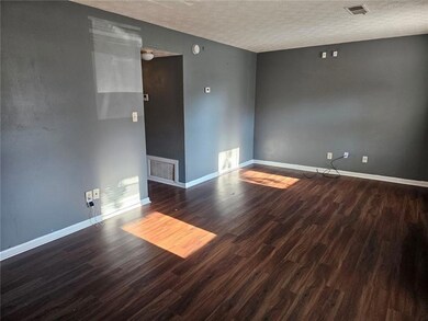 Spare room with a textured ceiling, wood finished floors, and baseboards