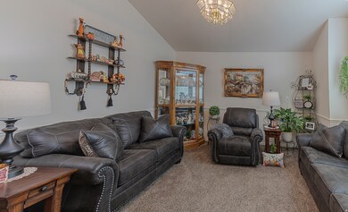 Carpeted living room featuring lofted ceiling and a chandelier