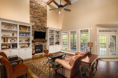 Living room with stone fireplace and gas logs. High ceilings with built in bookshelves.  