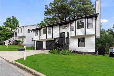 Split foyer home with driveway, an attached garage, a chimney, and a front lawn