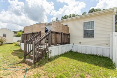 Back of house with a deck and a lawn