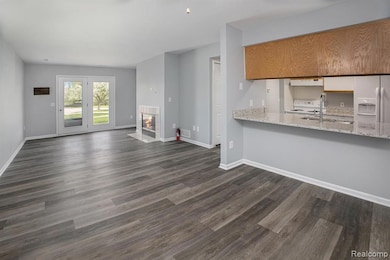 Unfurnished living room with a tiled fireplace and dark wood-style floors