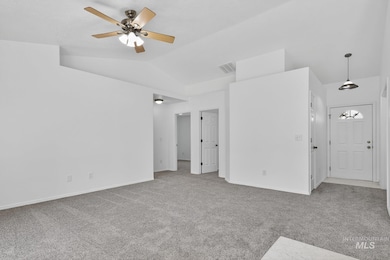 Empty room with vaulted ceiling, carpet, and ceiling fan