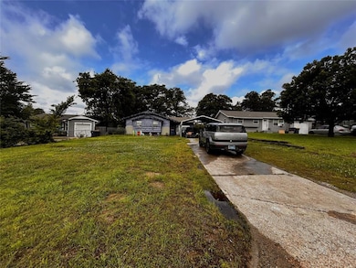 View of front of property featuring a carport, driveway, and a front yard
