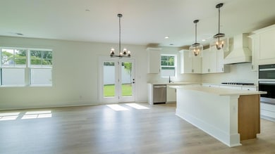 Kitchen featuring a chandelier, stainless steel appliances, premium range hood, light countertops, and a kitchen island