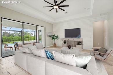 Living area featuring a raised ceiling, a sunroom, a ceiling fan, and light tile patterned floors