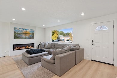 Living area with light wood-style flooring, a glass covered fireplace, and recessed lighting