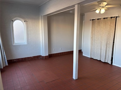 Tiled spare room with ceiling fan and brick wall