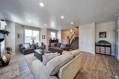 Living area with light wood-style flooring, recessed lighting, stairs, and a textured ceiling