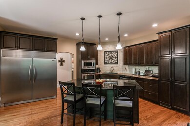 Open kitchen with granite, stainless steel appliances including a Frigidaire Professional Series refrigerator/freezer that stays with the home, and a large island