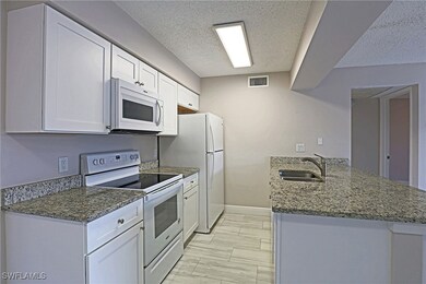 Kitchen with white appliances, a sink, a textured