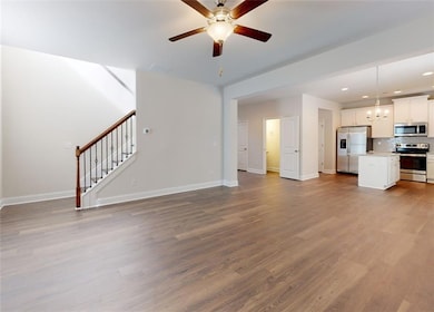 Unfurnished living room with a ceiling fan, stairs