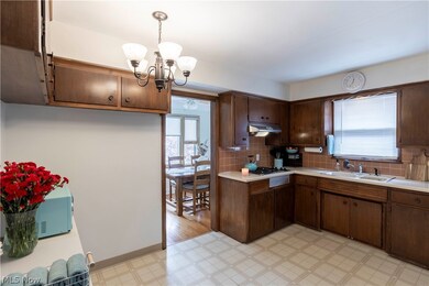 Kitchen featuring backsplash, hanging light fixtures, a chandelier, sink, and light tile floors