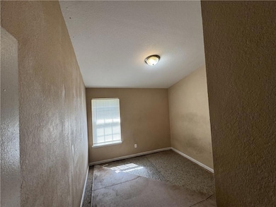 Carpeted spare room with a textured wall, baseboar