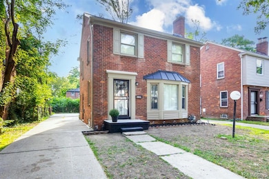 Colonial house featuring brick siding, a chimney, and a standing seam roof