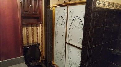 This bathroom features black tub, shower, and toil