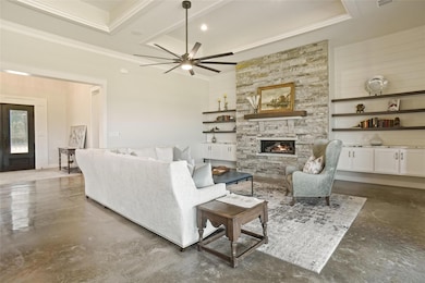 Living room with a stone fireplace, crown molding,