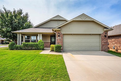 View of front of house with brick siding, concrete driveway, a garage, a front yard, and covered porch