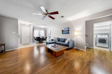 Living area with light wood-style floors, a textured ceiling, a ceiling fan, stairway, and separate washer and dryer