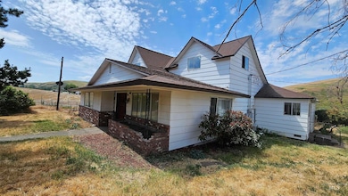 View of property exterior featuring a porch, roof with shingles, and a lawn