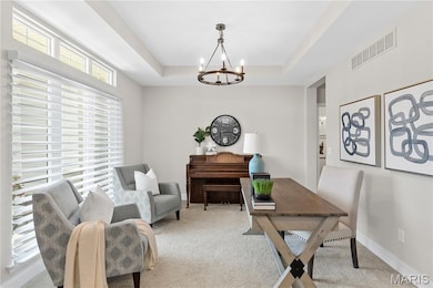 Home office with a tray ceiling, carpet flooring, and a chandelier