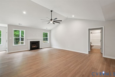 Unfurnished living room featuring lofted ceiling, a fireplace with flush hearth, light wood-style floors, recessed lighting, and ceiling fan