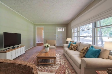 Living area featuring a textured ceiling, baseboards, and ornamental molding