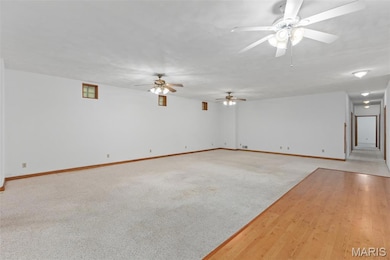 Unfurnished living room featuring light wood-type flooring, light colored carpet, and ceiling fan