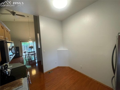 Kitchen has wood-style flooring, freestanding refrigerator, ceiling fan, stainless steel electric self cleaning range oven.