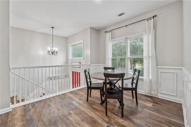 Dining space featuring wood finished floors, a wainscoted wall, a chandelier, and a decorative wall