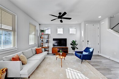 Living area with ceiling fan, baseboards, wood fi