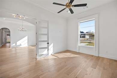 Spare room with ornamental molding, light wood-style floors, a chandelier, ceiling fan, and arched walkways