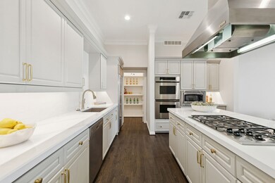 Kitchen with range hood, stainless steel appliances, white cabinetry, ornamental molding, and dark wood-style flooring