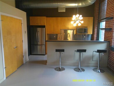Kitchen with a kitchen bar, stainless steel appliances, brick wall, and a chandelier